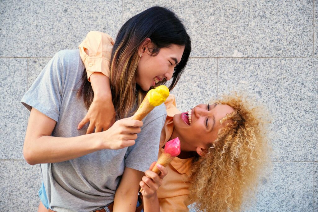 Two multiracial happy friends with ice creams smiling in summer.