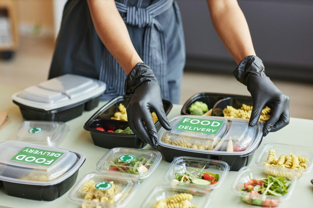 Woman carefully packing food delivery orders in plastic containers