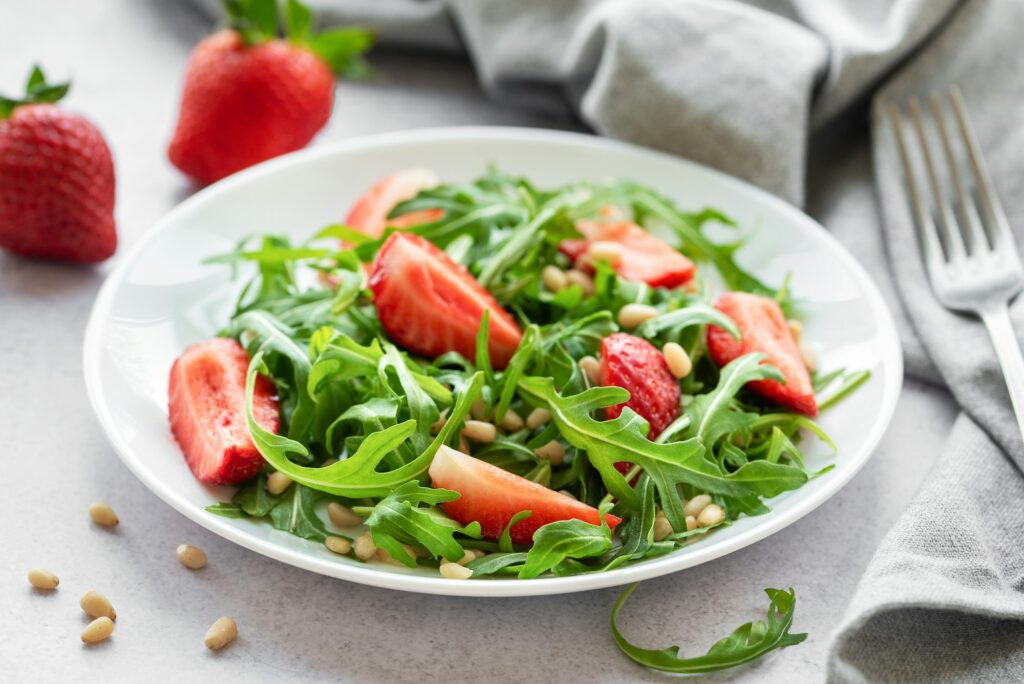 fresh strawberry arugula salad with pine nuts served on a bright day