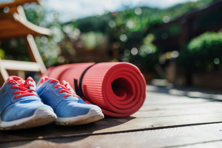 Exercise mat and trainers outdoors on a terrace in summer.